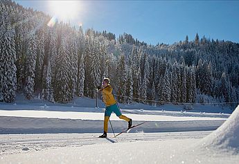 Skilehrer, Privatskilehrer, Skischule, Freeride Gelände, Skikurs für Kinder und Erwachsene,  Skitouren, Gruppen, Langlaufschule, Skating-Lehrer, staatlich geprüfter Skilehrer Allgäu, Tirol, Vorarlberg. Ein Mann mit Thermokleidung beim laufen im Winter auf zwei Skiern mit Stöcken auf einer Skipiste und Langlaufloipe.
