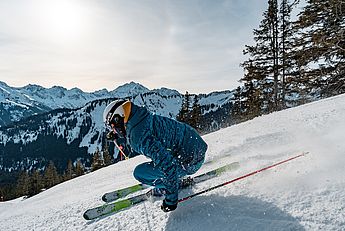 Skilehrer, Privatskilehrer, Skischule, Freeride Gelände, Skikurs für Kinder und Erwachsene, Skiführer, Skitouren, Gruppen, Langlaufschule, Skating-Lehrer, Allgäu, Tirol, Vorarlberg.  Ein Mann auf Ski fährt den Berg hinunter im Winter. Er fährt eine Kurve in perfekter Skitechnik. Die Skischule ist privat buchbar für Gäste und Einheimische im Allgäu.