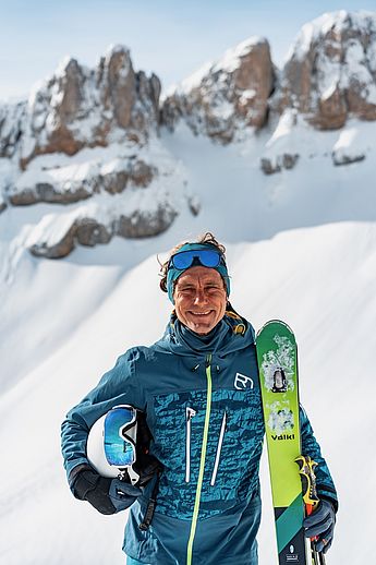 Skilehrer, Privatskilehrer, Skischule, Freeride Gelände, Skikurs für Kinder und Erwachsene,  Skitouren, Gruppen, Langlaufschule, Skating-Lehrer, staatlich geprüfter Skilehrer Allgäu, Tirol, Vorarlberg. Ein Mann mit Ski steht vor einem Allgäuer Berg und holt Gäste für den Unterricht auf Ski ab - vor dem Kurs bei Sonnenschein.